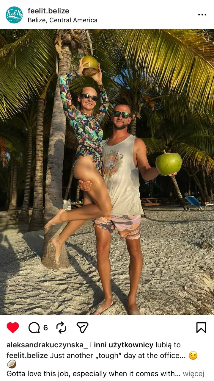 Hosts Szymon and Kamila on a Belize beach holding fresh coconuts under palm trees